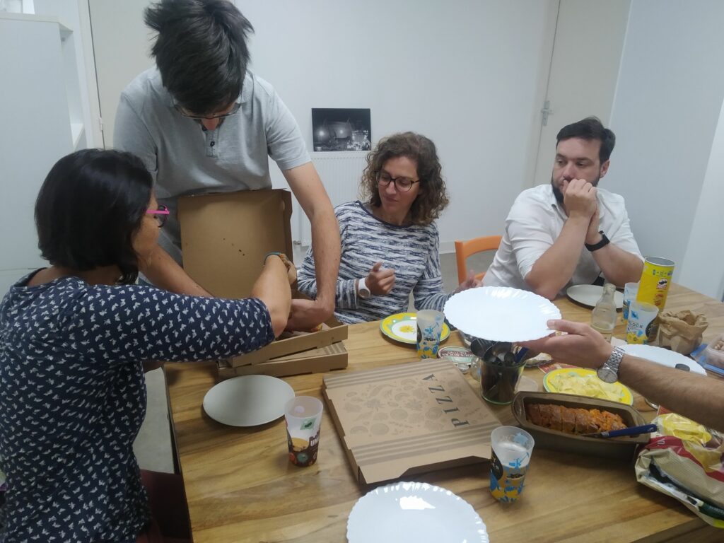 4 personnes autour d'une table en train de se partager une pizza